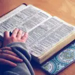 Open Bible with a person's hand on the page