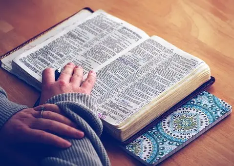 Open Bible with a person's hand on the page
