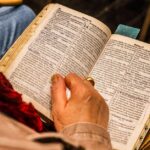 A person reading a Bible indoors, symbolizing spirituality and devotion.