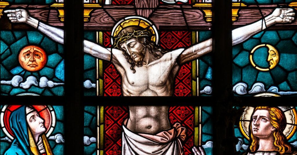 Detailed stained glass depiction of the crucifixion featuring Christ and religious icons.