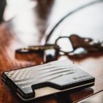 A wallet and keys placed on a wooden table with selective focus and warm tones.
